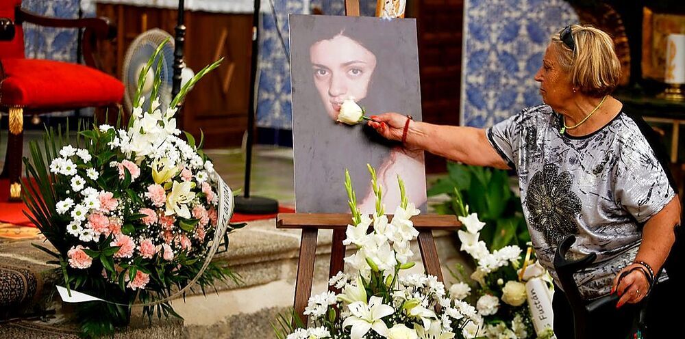 Una vecina pasa una rosa por el retrato de Belén tras el funeral.