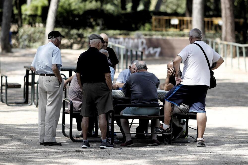 Varios pensionistas juegan al dominó en un parque de Madrid